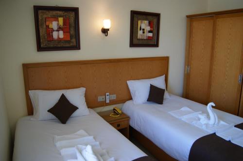 赫尔格达Palm Inn City Hotel的两张睡床彼此相邻,位于一个房间里