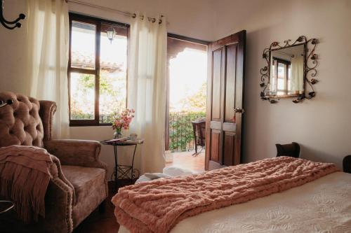 危地马拉安地瓜Autumn in Antigua Boutique Hotel的一间卧室配有一张床、一把椅子和镜子