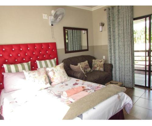 贝拉贝拉BelaBela Guesthouse的一间卧室配有一张带红色床头板的床和一张沙发