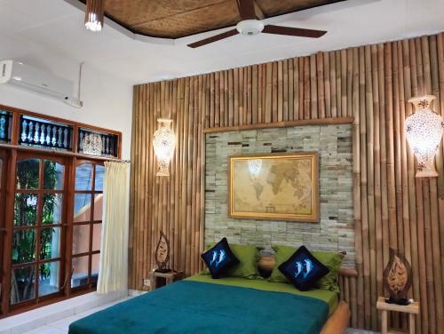 罗威那Kaia Lovina Guest House Junior Suite的一间卧室设有绿色的床和砖墙