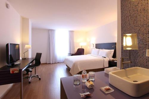 墨西哥城瑙卡尔潘嘉年华酒店的配有一张床和一张书桌的酒店客房