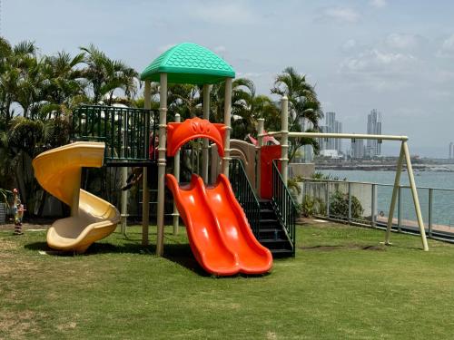 巴拿马城Apartamento en Panama y Punta Pacífica, Céntrico y Costa de Panamá的一个带两个滑梯和遮阳伞的游乐场