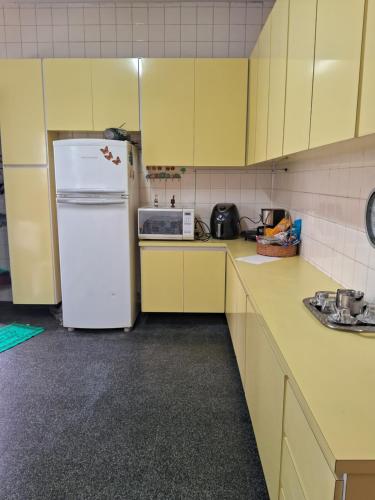 圣保罗Casa Térrea SP Expo e C Paralimpico的厨房配有黄色橱柜和白色冰箱