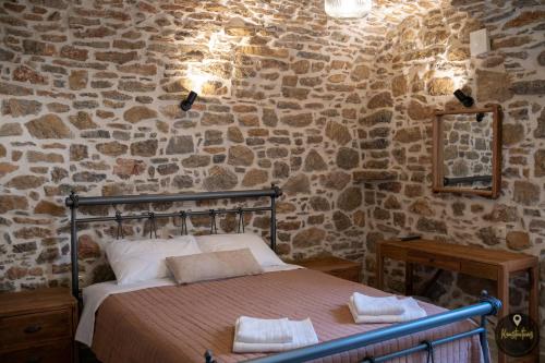 PyrgiSKINOS rooms and apartment的卧室配有一张石墙床