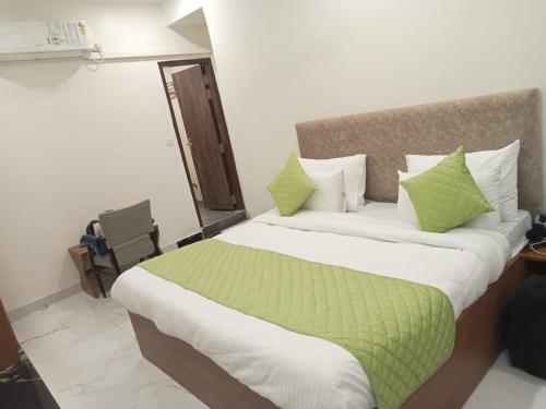 新德里Hotel Fortune Residency的一间卧室配有一张带绿色和白色枕头的大床