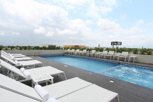 梅里达梅里达嘉年华酒店的一座带白色躺椅的建筑屋顶上的游泳池