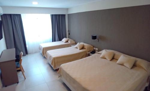 萨尔塔Hotel Alvarado Suites的酒店客房设有三张床和窗户。