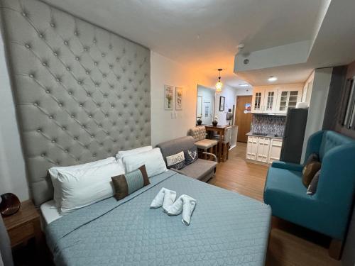 大雅台CozyVilla at Pine Suites Tagaytay 2BR or Studio with FREE PARKING的一间卧室配有一张床和一张蓝色椅子,还设有一间客厅