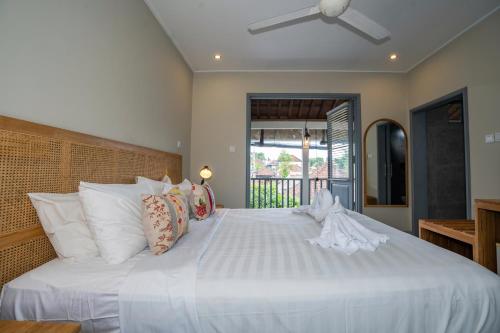 乌布孔雀旅馆的卧室配有白色大床和白色枕头