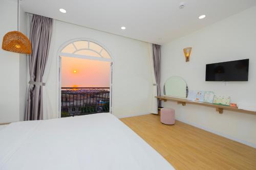 富国Lily House Hotel Phu Quoc的一间卧室设有一张床、一台电视和一个窗口。