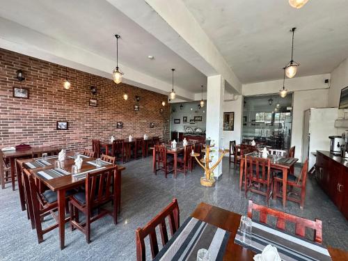 努沃勒埃利耶Royal Pearl Hills的餐厅设有木桌和椅子,拥有砖墙
