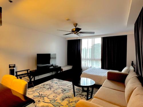 碧瑶Forest Lodge at Camp John Hay privately owned - Deluxe Queen Suite with balcony and Parking 269的酒店客房设有一张沙发和一张床