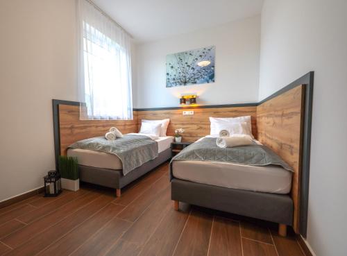 巴拉顿诺尔马迪Silver Home Apartman "A"的卧室设有两张床,铺有木地板,设有窗户。