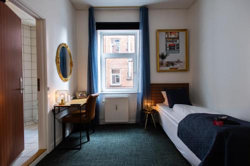 欧登塞Milling Hotel Ansgar的一间卧室配有一张床、一张书桌和一个窗户。
