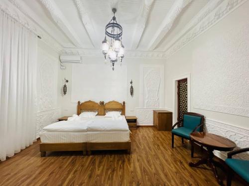布哈拉Best Hotel Muqaddam的一间卧室配有一张床、一张桌子和一个吊灯。