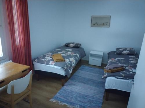 海门林纳Saarnimaja的客房设有两张床、一张桌子和一张书桌。