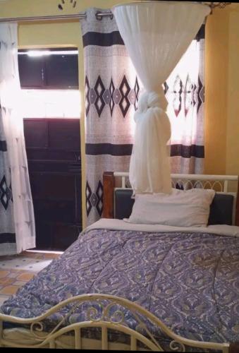 KakamegaTHE FARM BAR AND RESTAURANT的一间卧室配有一张带窗帘的床和窗户