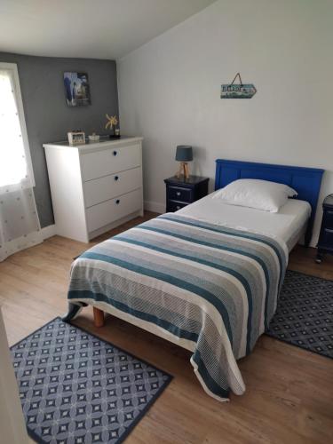 欧登日Gîte Domangé-Audenge的一间卧室配有一张带条纹毯子的床和梳妆台