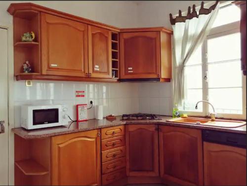 丰沙尔Vila São Gonçalo的一间带木制橱柜和微波炉的厨房