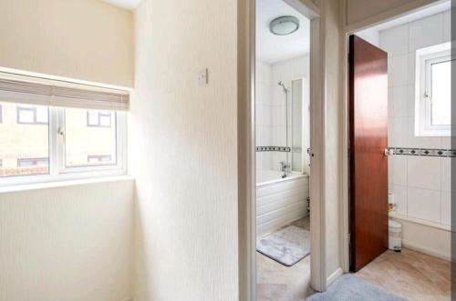 伦敦London Stratford Holiday Home的带浴缸、卫生间和窗户的浴室