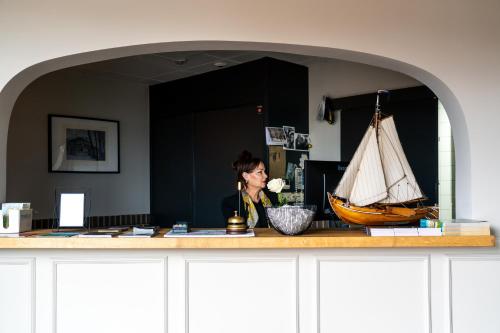 哈尔德韦克Restaurant & Hotel Monopole Harderwijk的站在柜台后面的女船,有船模