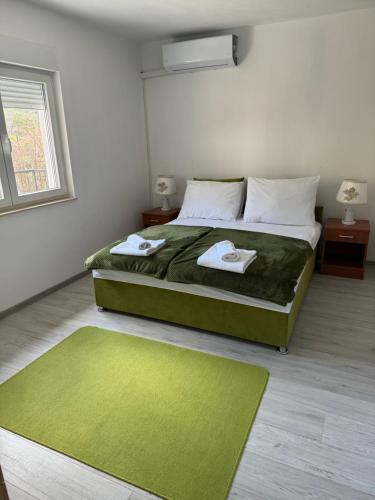 StolacCuprija _apartments的一间卧室配有绿床和2条毛巾
