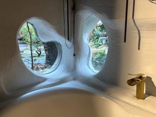 松山考米卡麦哈玛民宿的带浴缸的浴室和2扇圆形窗户