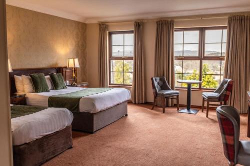 斯特拉诺勒Kee's Hotel的酒店客房带两张床和一张桌子以及椅子。