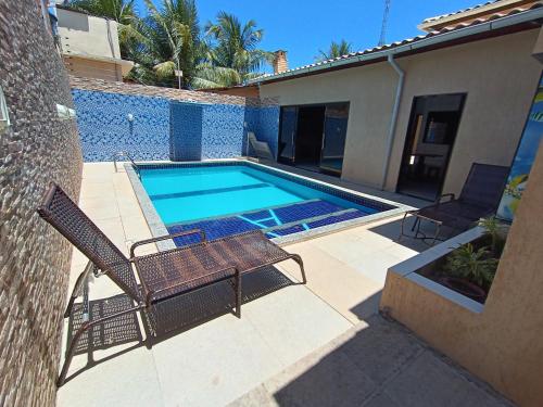 马拉戈日Casa MARAGOGI com PISCINA e área GOURMET COMPLETA的一座房子旁带两把椅子的游泳池