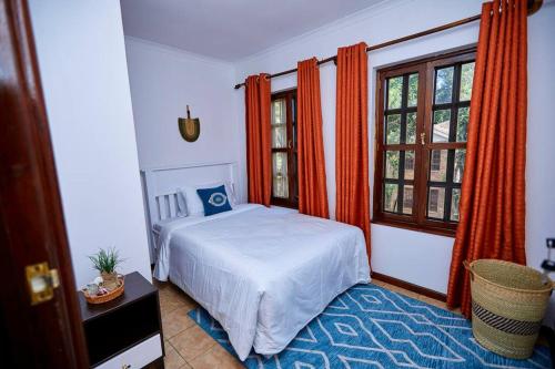 NgateuPeaceful and Cozy Home in Arusha的一间卧室配有床和带橙色窗帘的窗户。