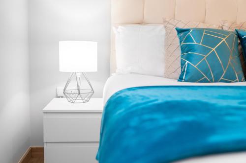 Modern 2 Bedroom Apartment - Off-street Parking - Top Rated - 1aS的一张带蓝色毯子的床和床头柜上的灯