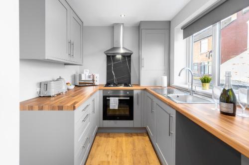 Modern 2 Bedroom Apartment - Off-street Parking - Top Rated - 1aS的厨房配有白色橱柜和木制台面
