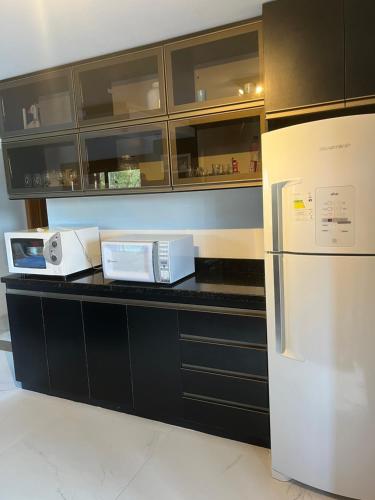圣弗朗西斯科-迪保拉Estadia Barragem do Salto - Casa Mugam的厨房配有黑色橱柜和白色冰箱。
