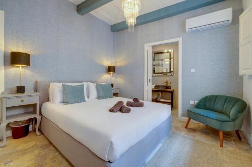 森格莱阿Charming Maltese Townhouse in Senglea的卧室配有一张白色大床和一张绿色椅子