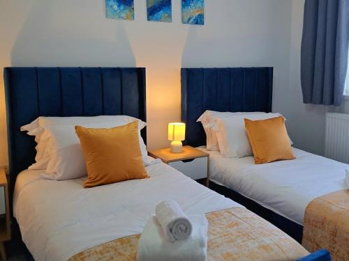 切斯特Cozy, Charming 3-Bedroom Home in Chester- Free Parking- Sleeps Up To 6的配有蓝色窗帘的客房内的两张床