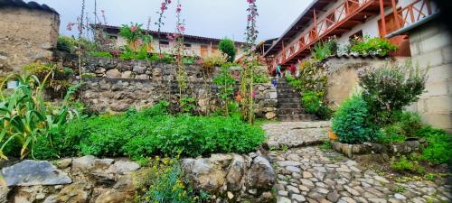 HuanipacaHospedaje Wayna Pakaq的花园内有鲜花和植物的石墙