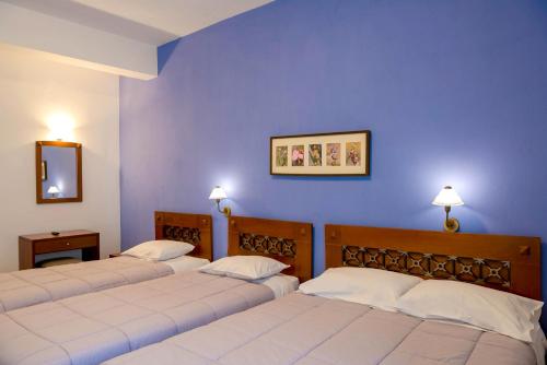特尔斐阿尔特弥斯酒店的蓝色墙壁的客房内的三张床