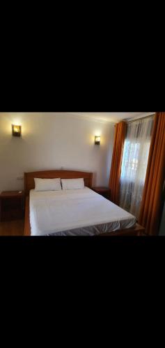 NsazomoN et M Inn - Hébergement的一间卧室配有一张带白色床单的床和一扇窗户。