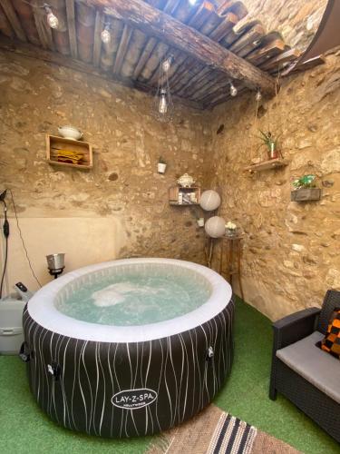 马莱莫尔Logement atypique avec jacuzzi inclus的石墙房间内的热水浴缸