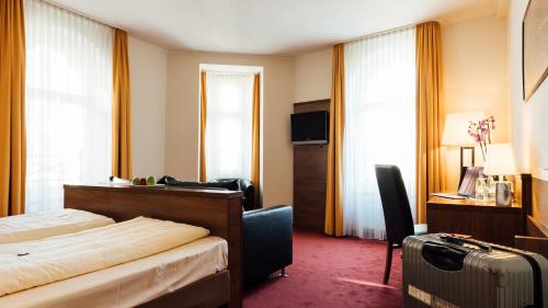 伍珀塔尔阿尔卡德酒店的酒店客房,带一张床和行李箱