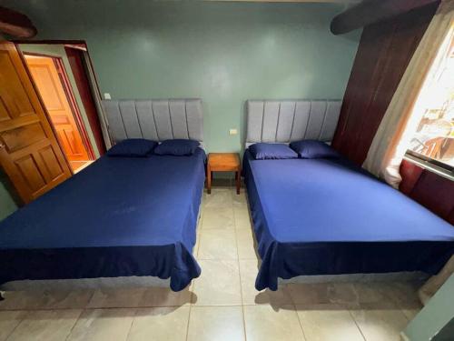 卡里略Tabaco Lodge #2 a solo 5 minutos de Playa Carrillo的客房内的两张床和蓝色床单
