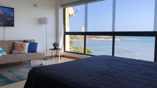 波拉马尔Apart. con aire, frente al mar的一间卧室配有一张床、一张沙发和一个大窗户