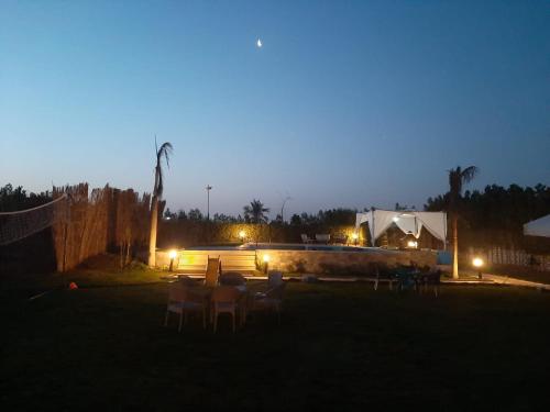 El-QaṭṭaDija's holiday rental的一群桌子和椅子在晚上在院子里