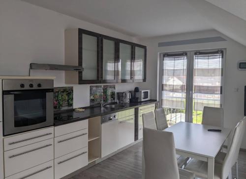 鲁斯特Kempf Apartments的厨房配有白色橱柜和桌椅