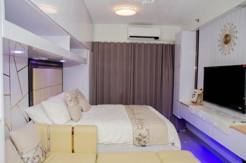 马尼拉Condo Home Near MOA and Airport的一间卧室配有一张床、一张沙发和一台电视。