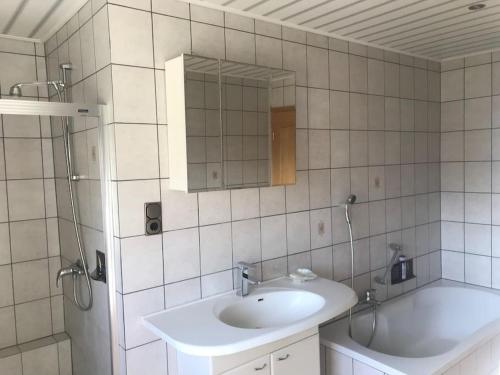Reichshof Urlaub im Grünen - Ferienwohnung EG im Brunnenhof的浴室配有盥洗盆、镜子和浴缸