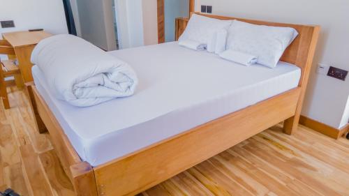 MugumuNyitika Hotel的一张带白色床单和枕头的床