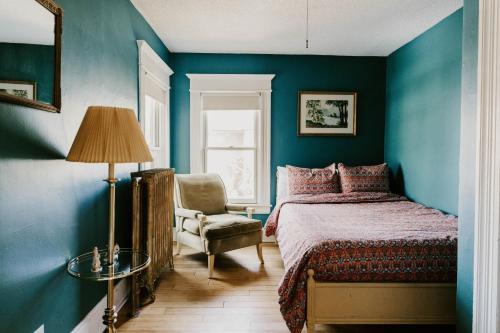 圣保罗Retro Gem Box Victorian Steps from Irvine Park的卧室拥有蓝色的墙壁,配有一张床和椅子