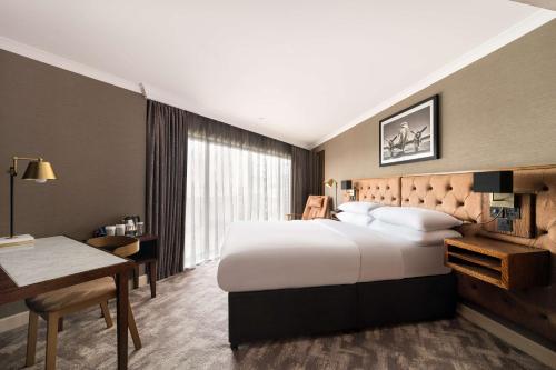 泰恩河畔纽卡斯尔希尔顿纽卡尔斯国际机场双树酒店的酒店客房设有一张大床和一张书桌。