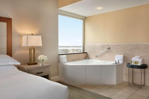 大洋城海滩城市希尔顿套房酒店的带浴缸、床和窗户的浴室
